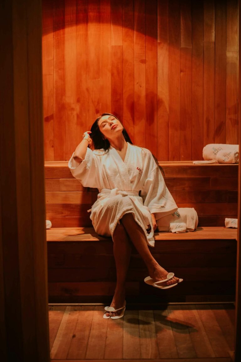 Woman in robe relaxing in a warm sauna, enjoying a calming moment.